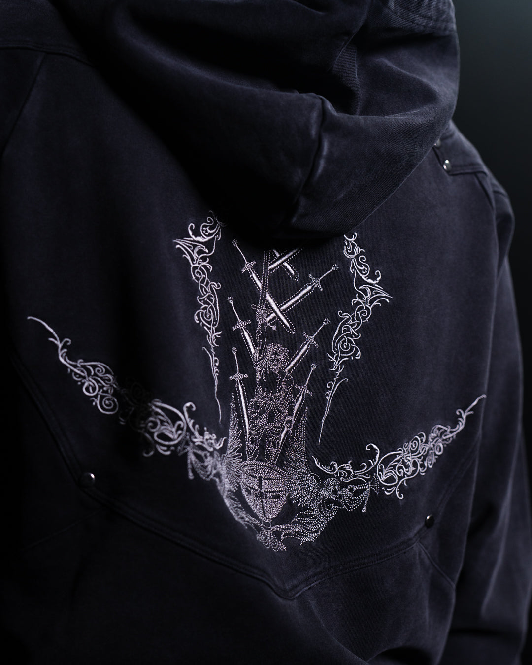 Black hoodie with intricate white embroidery on a dark background