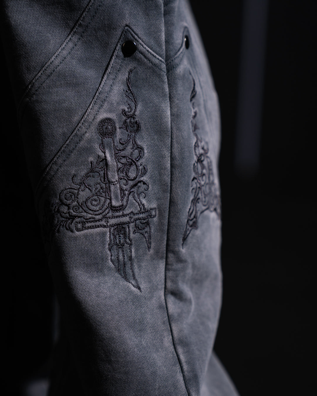 Close-up of a dark fabric with intricate embroidery on a black background