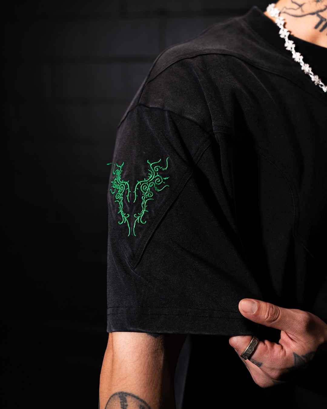 Black t-shirt with green design on sleeve against a dark background