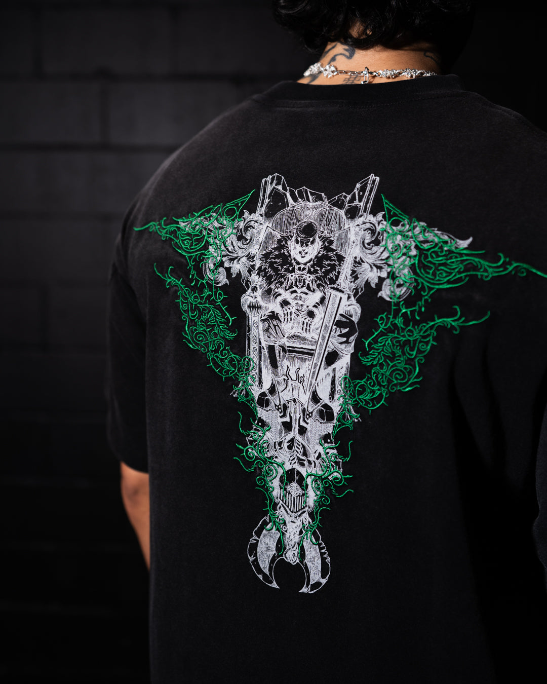 Black t-shirt with a detailed graphic design on the back against a dark background.
