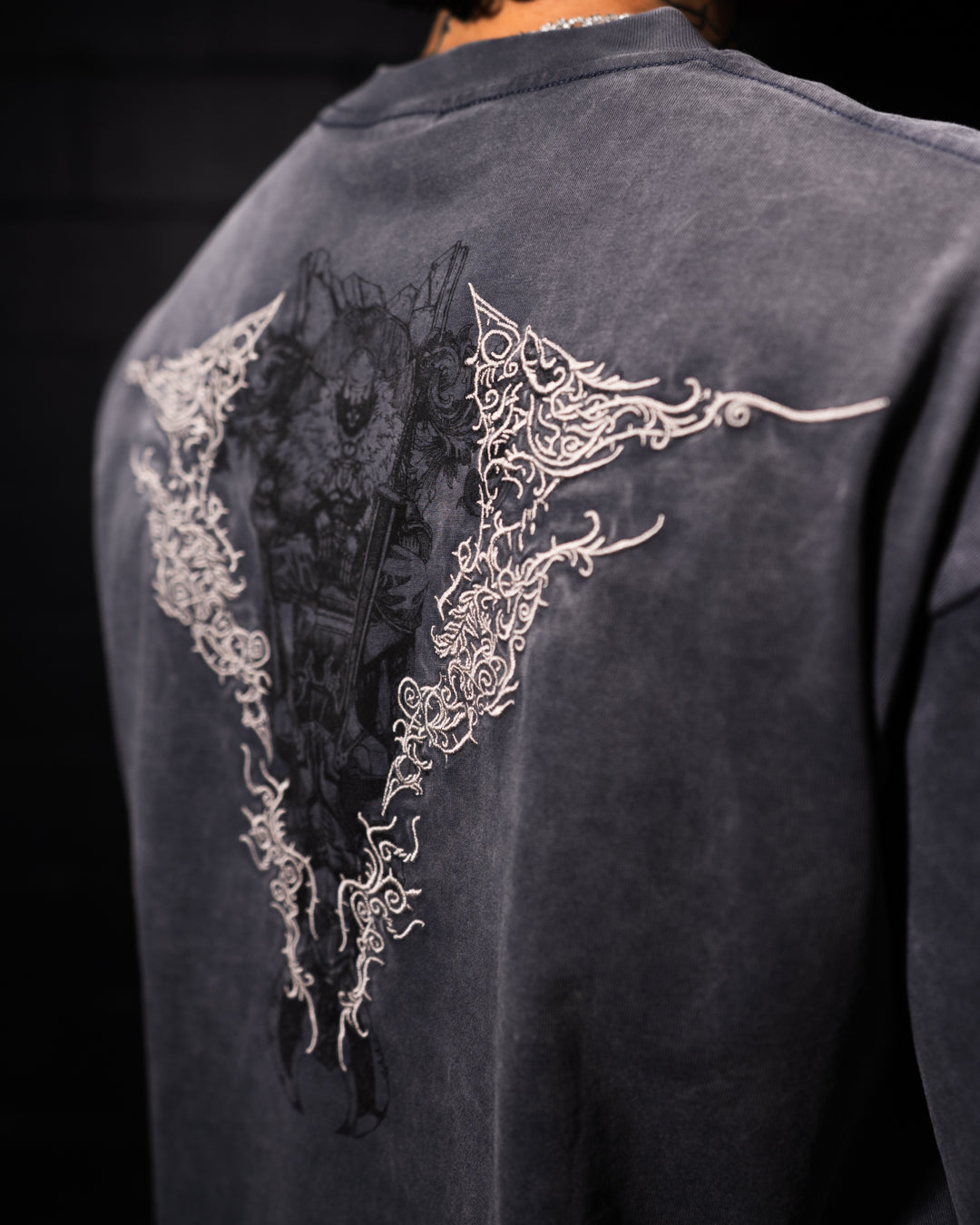 grey t-shirt with intricate white designs on the back against a black background