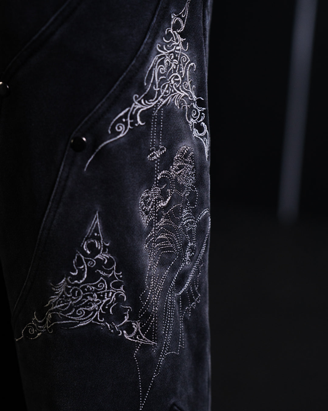 Black garment with intricate white embroidery on a dark background