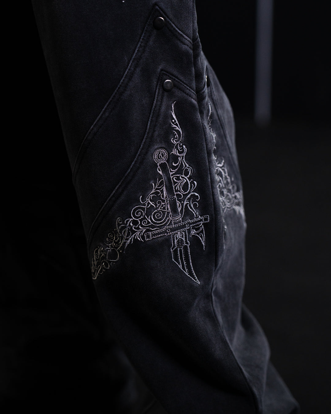 Black fabric with intricate white embroidery on a dark background