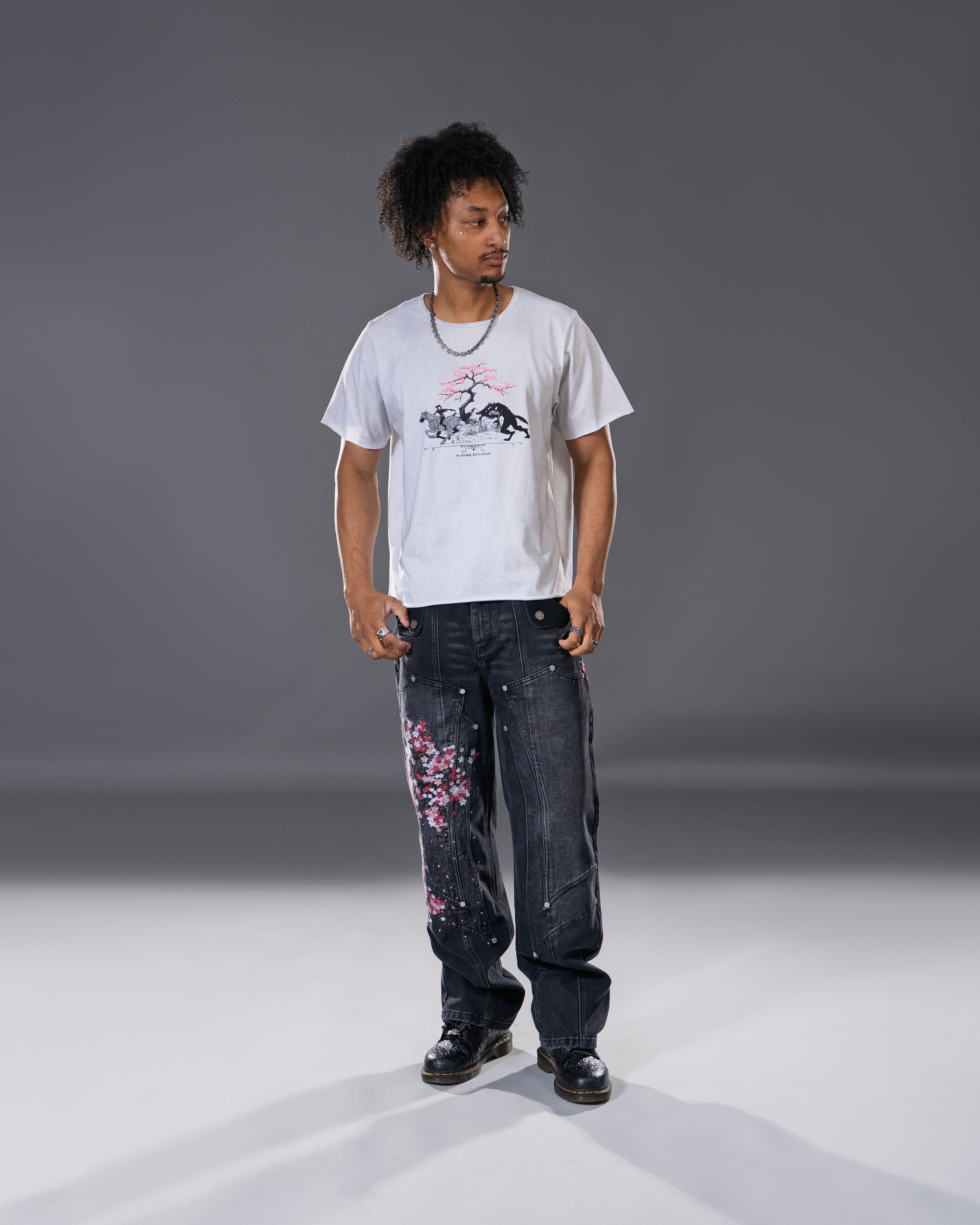 Black denim jeans with cherry blossom floral embroidery and armored inspired paneling.
