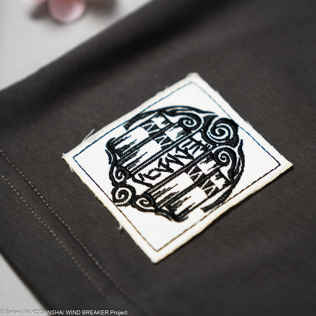 Embroidered logo patch on a dark grey t-shirt.