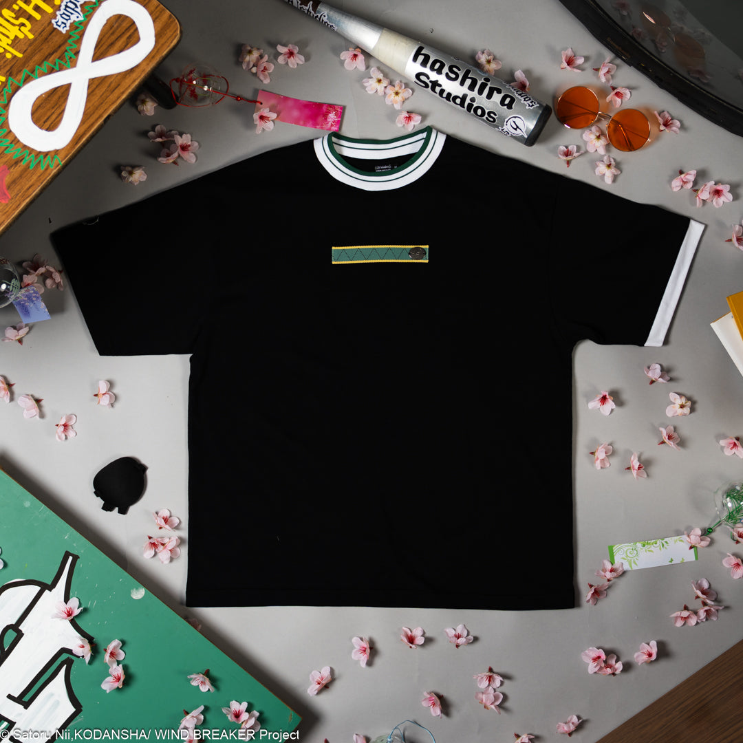 Black t-shirt with a small logo on a gray surface.