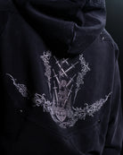 Black hoodie with intricate white embroidery on a dark background
