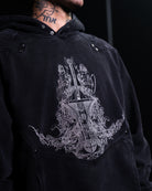 Black hoodie with intricate white embroidered design on a black background