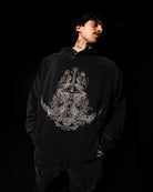 Person wearing a black hoodie with a white embroidered design on a black background