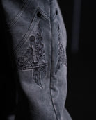 Close-up of a dark fabric with intricate embroidery on a black background