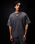 Person wearing a dark gray t-shirt with visible tattoos against a black background