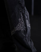 Black fabric with intricate white embroidery on a dark background