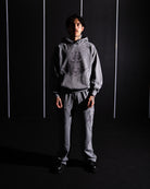 Person wearing a gray hoodie and pants against a dark background