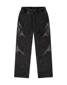 Black sweatpants with embroidered elements, metal rivets and drawstring cord on a white background. 