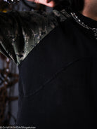 Close-up of a person wearing a black t-shirt with a camouflage pattern on the shoulder.