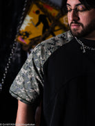 Person wearing a black t-shirt with camouflage shoulder detail. 