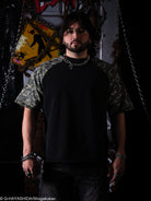 Man wearing a black shirt with camouflage sleeves against a dark background