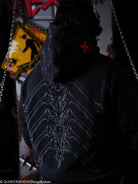 Person wearing a dark jacket with a spine design on the back, in a dark setting.