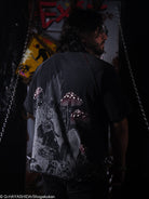 Person wearing a black t-shirt with a graphic design, standing in a dark setting.