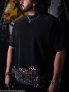 Person wearing a black t-shirt with intricate designs, standing against a dark background.