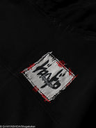Close-up of a black hoodie with a white patch featuring black text and red accents.