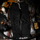 Black cargo pants on a dark surface with various items including a skull and chains.