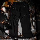 Black pants with a brand logo on a dark background with chains and tools.