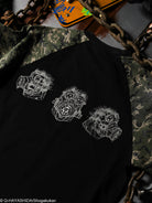 Black shirt with white printed character designs with camouflage sleeve details.