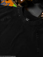 Close-up of a black shirt with visible stitching details, featuring a brand label.