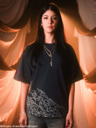 Person wearing a dark blue t-shirt with white design against a draped fabric background