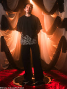 Person wearing black t-shirt in a room with draped fabric. 