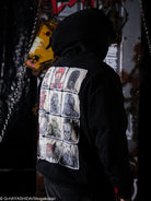 Person wearing a black hoodie with a unique design on the back, standing against a dark background.