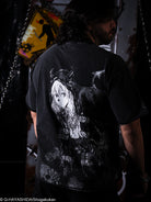 Person wearing a black t-shirt with an anime character design on the back, standing in a dark setting.