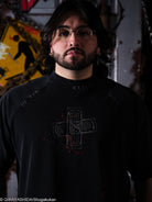 Man wearing a black t-shirt with a graphic design in a dark, industrial setting