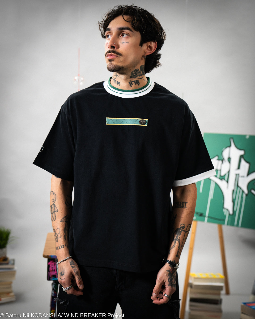 Person wearing a black t-shirt with a small logo, standing against a neutral background.