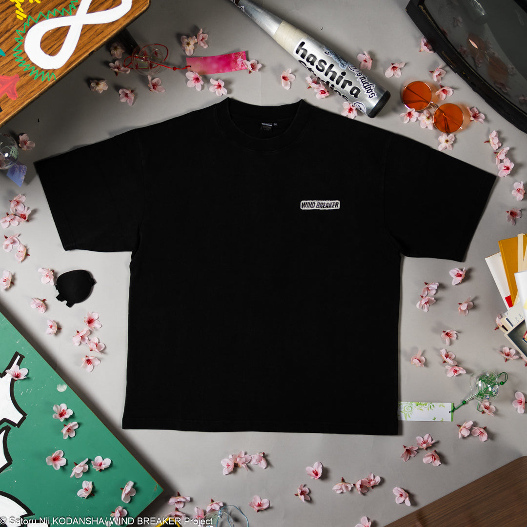 Black t-shirt with a logo on a gray surface with decorative items