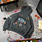 Gray hoodie with colorful patches on a gray surface with decorative items