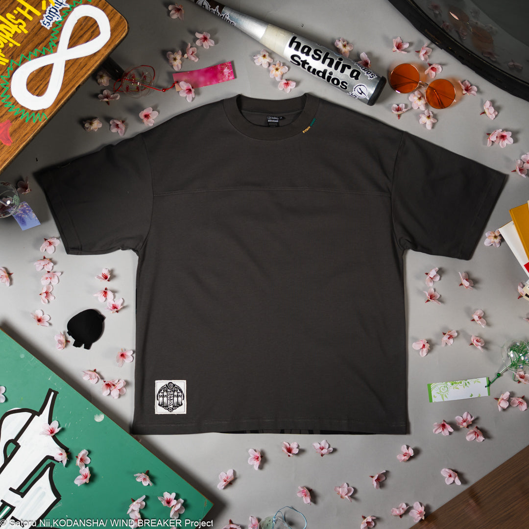 Grey t-shirt with a small logo on a gray background.