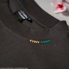 Close-up of a dark gray shirt with colorful embroidered design on a light gray background.