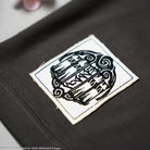 Embroidered logo patch on a dark grey t-shirt. 