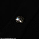 Metal button with engraved design on a dark textured background