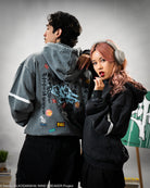 Two people wearing stylish hoodies with a gray background