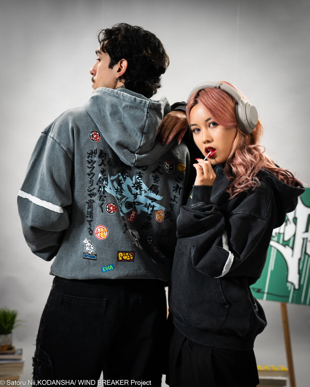 Two people wearing stylish hoodies for Wind Breaker with a gray background