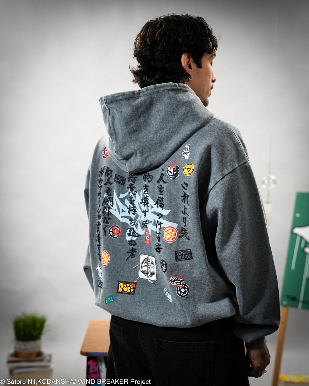 Person wearing a gray hoodie with various patches and embroidery on the back. 