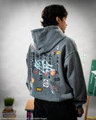 Person wearing a gray hoodie with various patches and embroidery on the back. 