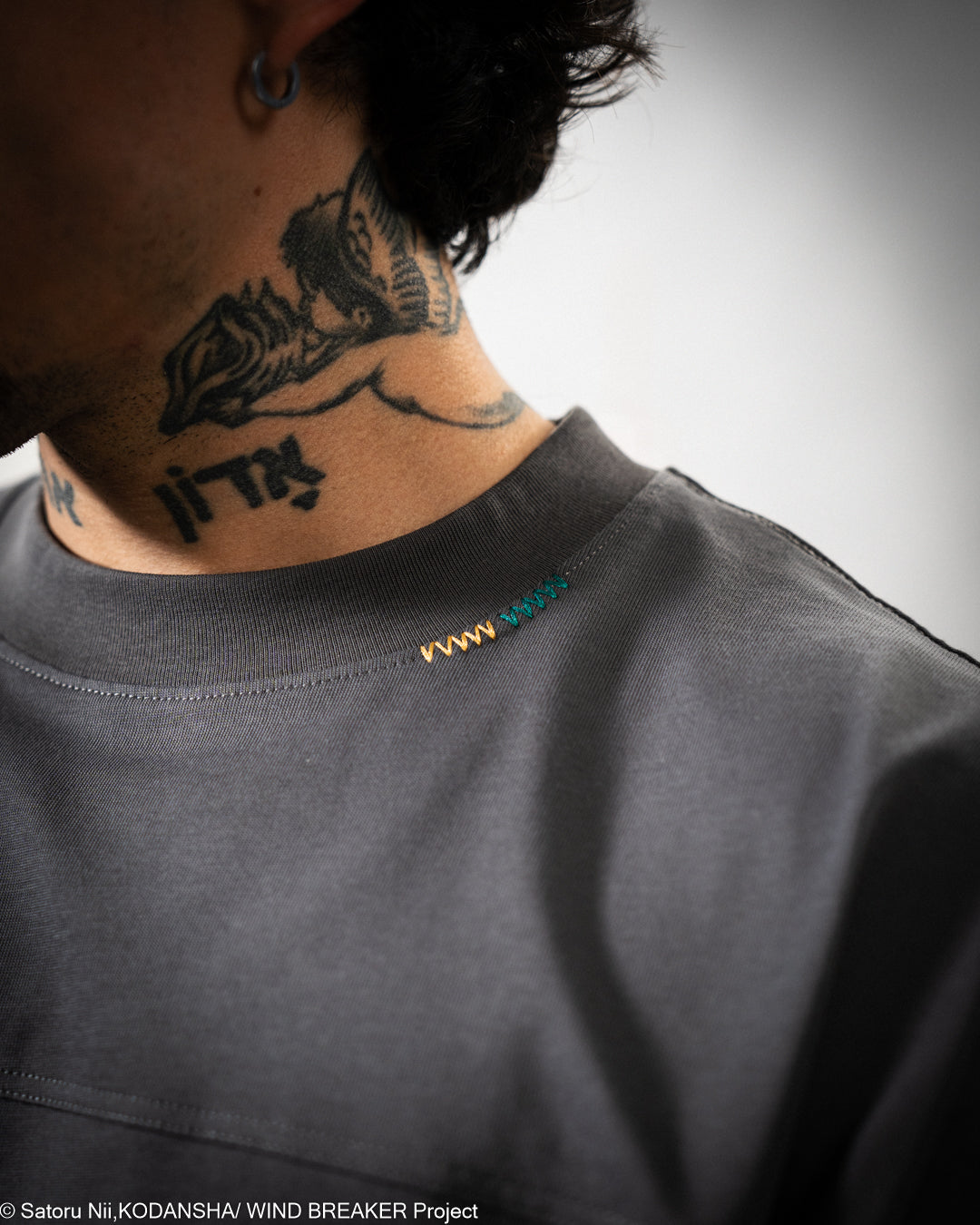 Person wearing a dark gray shirt with a small logo.