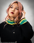 Person wearing a black coat with colorful collar, gray background