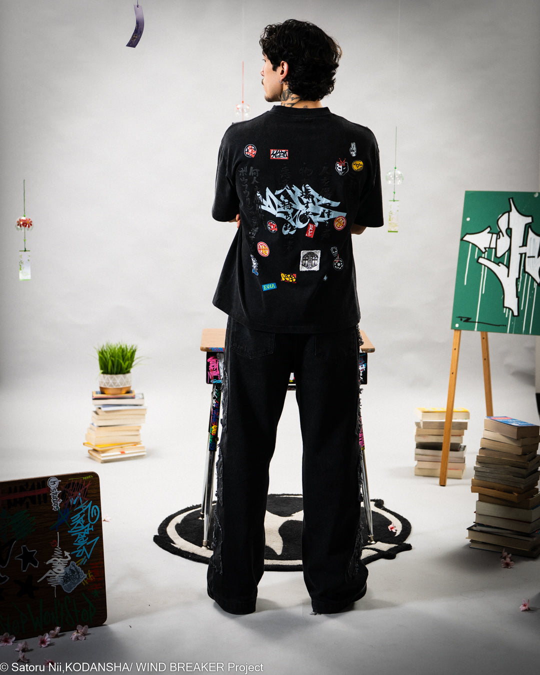 Person wearing a black outfit with colorful patches on a t-shirt. 