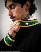 Person wearing a green and yellow patterned garment with a button, on a gray background.