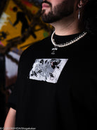 Person wearing a black t-shirt with a graphic design, standing against a blurred background.